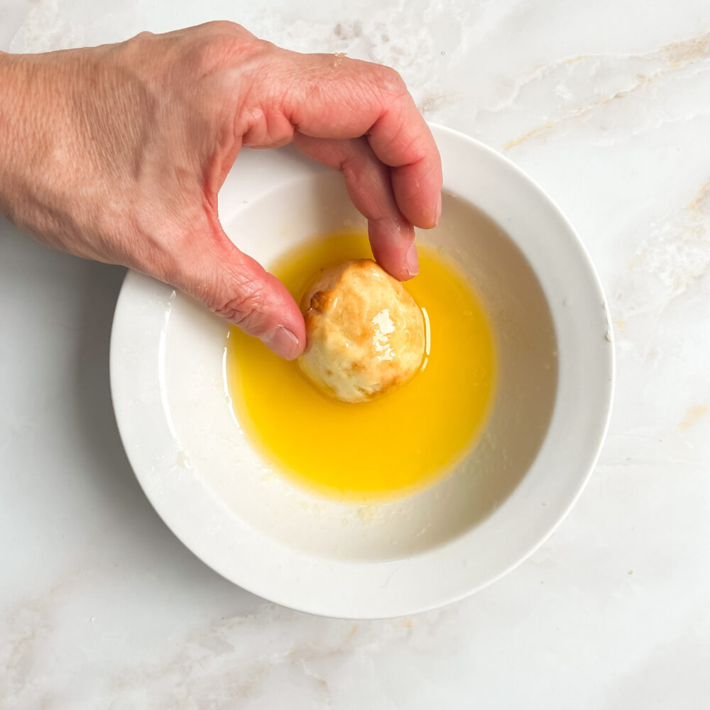 Mini beigne cuit au air fryer roulé dans le beurre avant de le plonger dans le sucre pour un enrobage croustillant