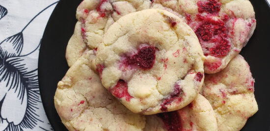 Assiette de biscuits moelleux aux framboises et pépites de chocolat blanc sur un comptoir de cuisine.