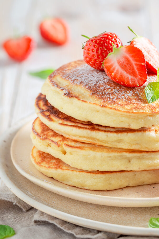 pancakes nature dans une assiette avec quelques fraises sur le dessus